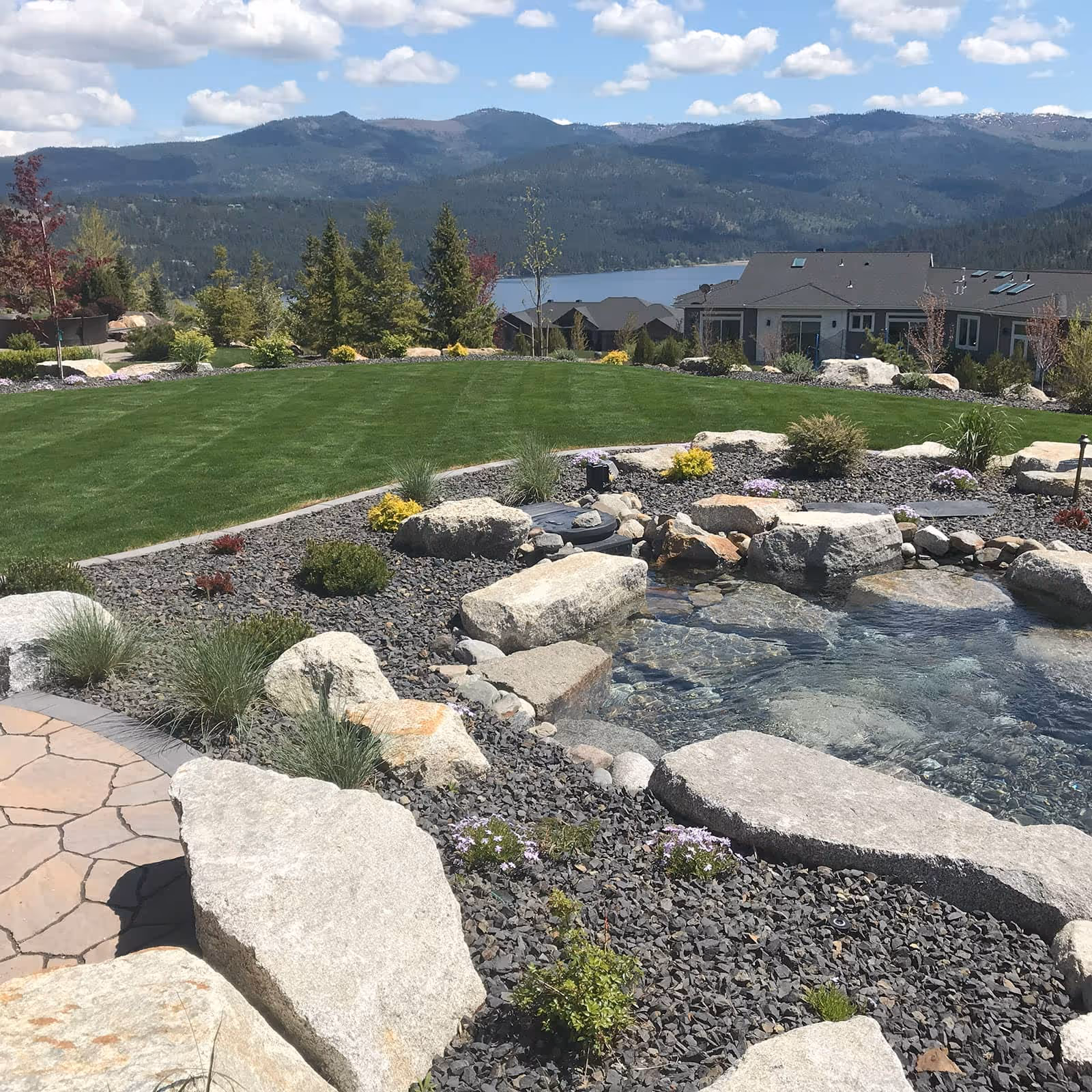 Landscaped grounds with stone water feature and striped lawn in Liberty Lake